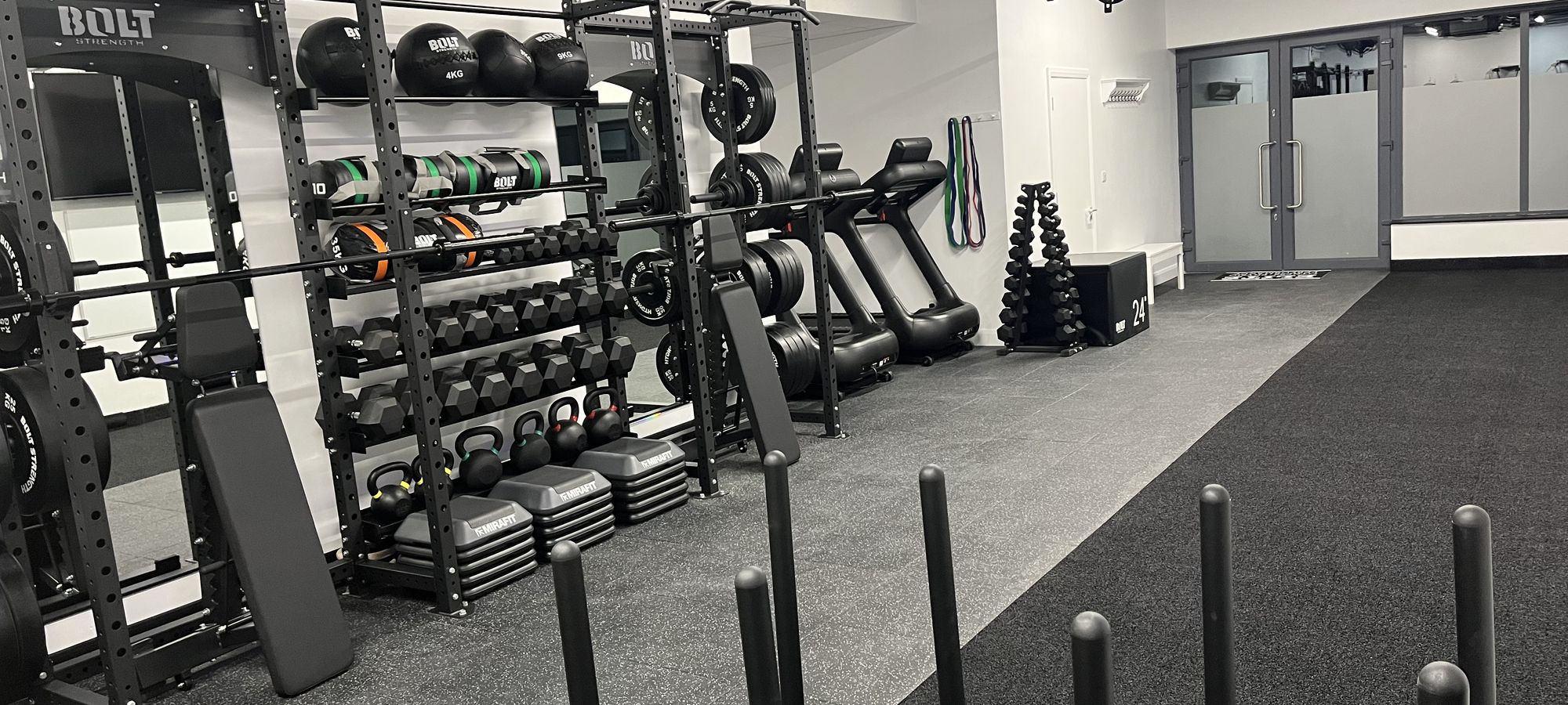 The width of the studio floor, rack, dumbbells, bench and treadmills beside the glazed door
